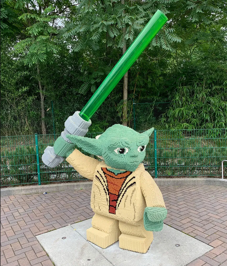 Giant LEGO Yoda statue holding a green lightsaber